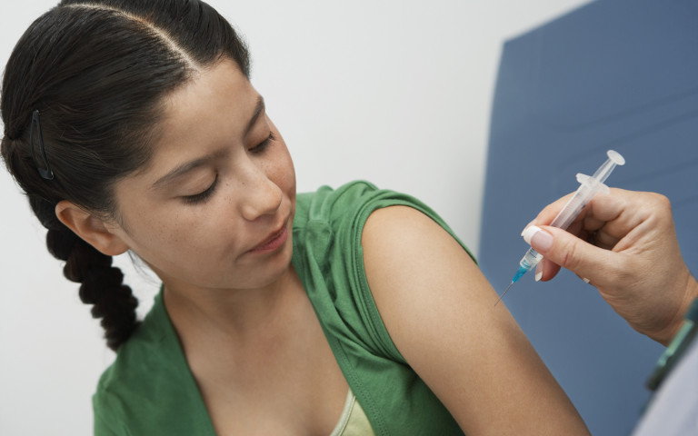 Meisje krijgt vaccinspuit van dokter in arm