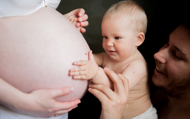 Bébé et père touchant le ventre d'une femme enceinte