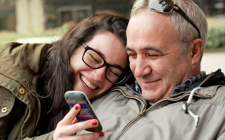 Vader en dochter met bril op samen kijken op smartphone