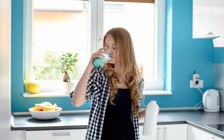 Une fille boit du lait dans la cuisine