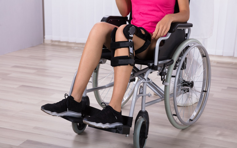 Vrouw in rolstoel met knie in brace