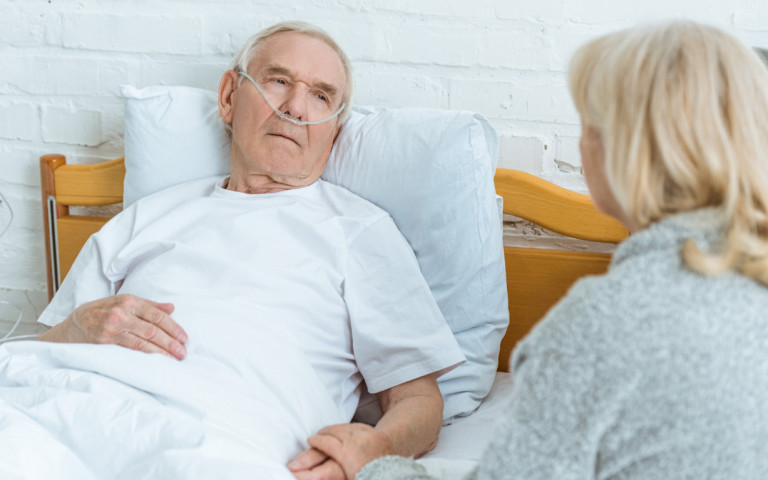 Homme alité avec aide femme à son chevet