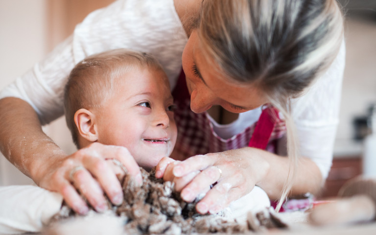 mama helpt kindje met handicap samen koken