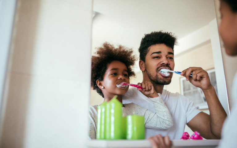 vader en zoon poetsen tanden voor spiegel