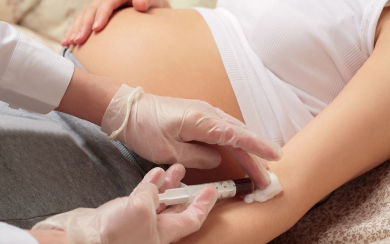 Dokter neemt bloedafname bij een zwangere vrouw.