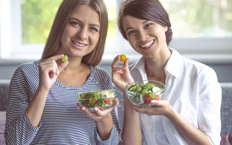 Twee vrouwen eten gezonde voeding uit een kommetje