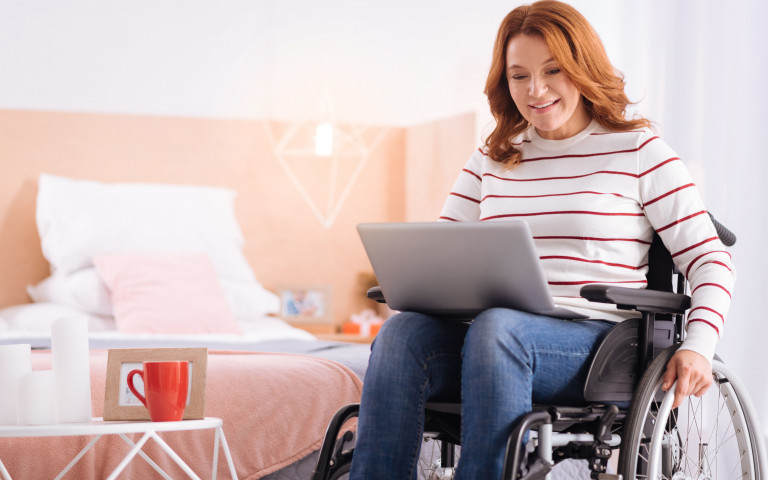vrouw in rolstoel werkt op laptop