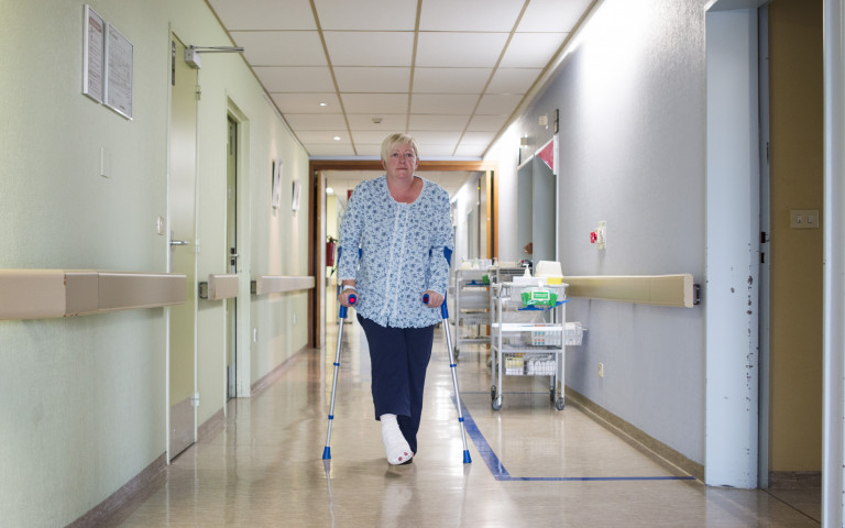 Vrouw op krukken door ziekenhuisgang