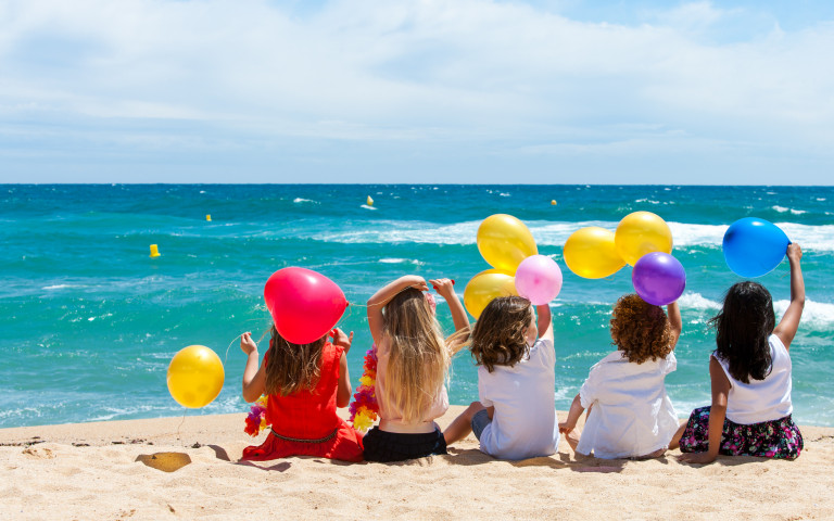 Jeunes enfants assis sur le sable devant la mer