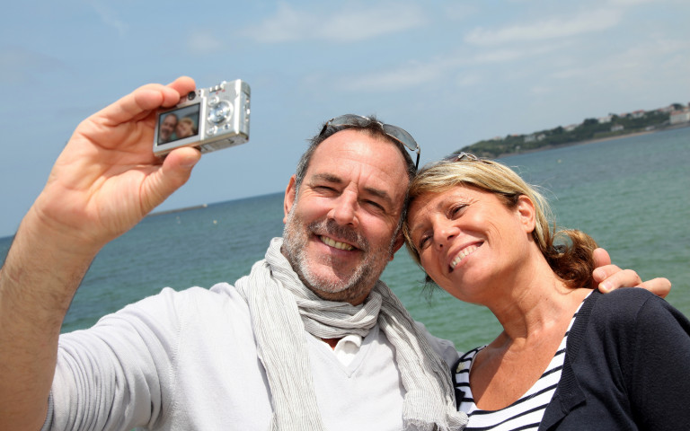 gepensioneerd koppel neem selfie aan zee