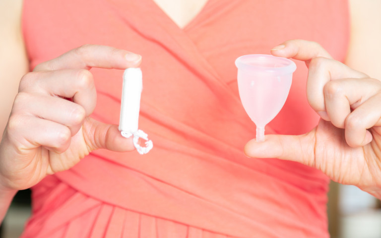 Vrouw houdt menstruatiecup en tampon vast