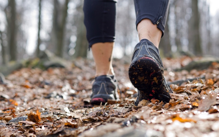 Personne qui marche en tenue de sport et baskets sur des feuilles 