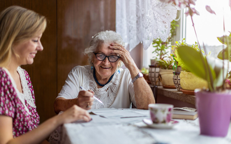 oude vrouw met jonge vrouw aan de keukentafel lachend