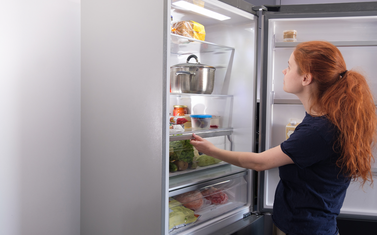 vrouw kijkt in koelkast