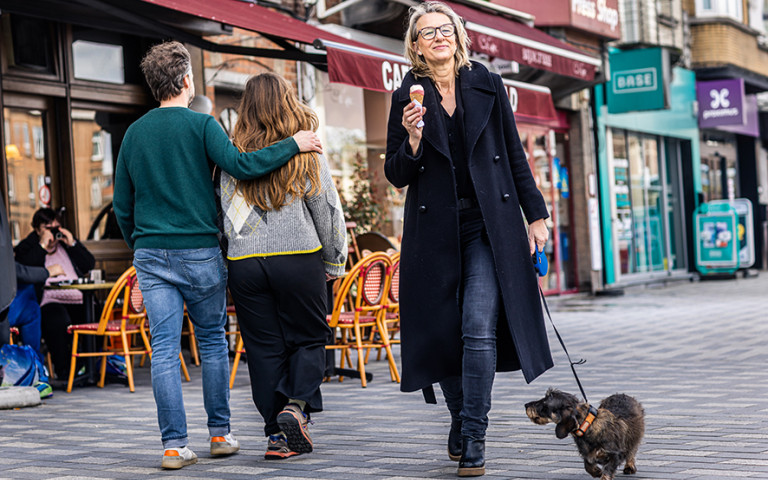 Vrouw wandelt door de stad met hond en ijsje