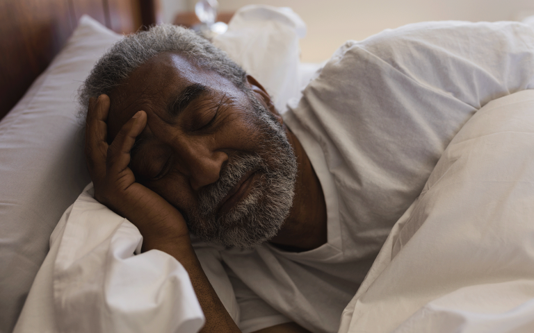 oude zwarte man ligt in bed te slapen