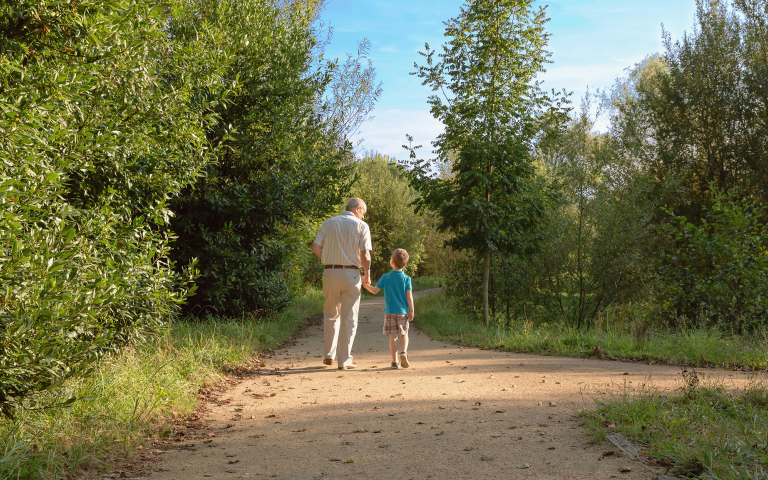 opa en kleinzoon wandelen samen door park in de zomer