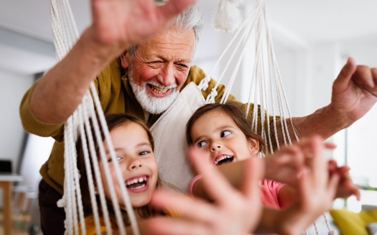 Opa speelt met zijn kleinkinderen in een hangstoel
