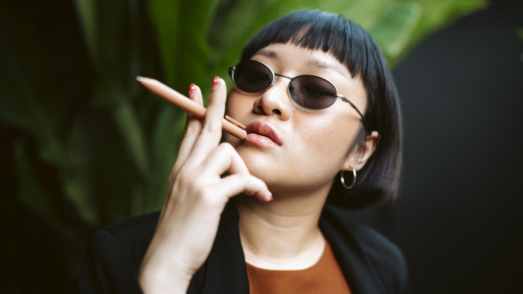 femme asiatique teins un stylo comme cigarette