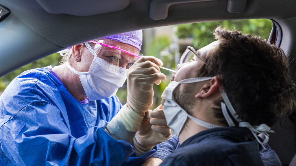 une infirmière fait un test coronavirus à un homme dans sa voiture