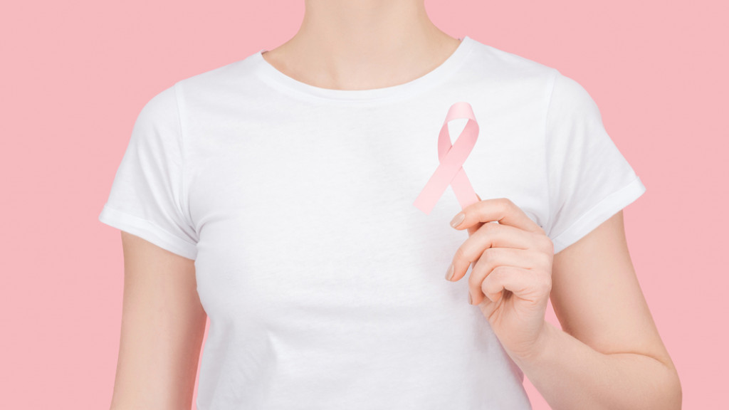 Femme avec un T-shirt blanc et qui tient un ruban rose dans sa main gauche