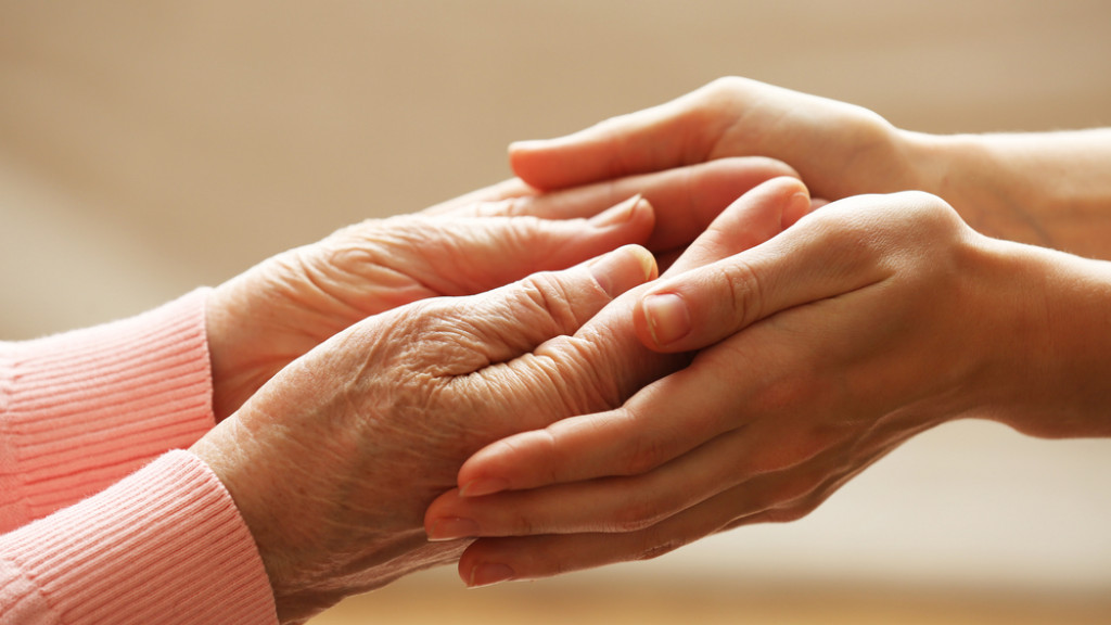 Mains jeunes qui tiennent les mains d'une personne âgée