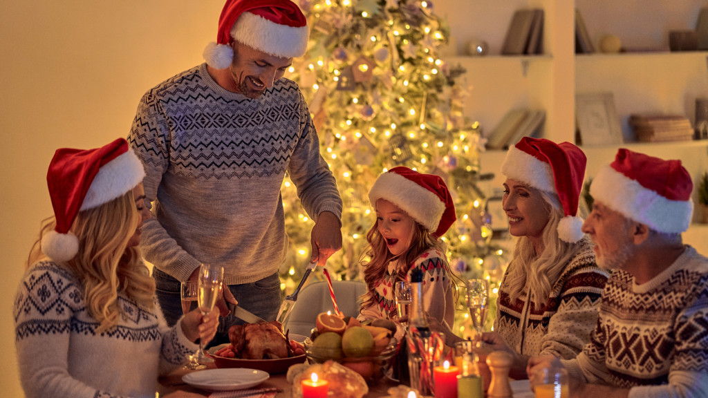 Gezin rond tafel met een kerstboom op de achtergrond