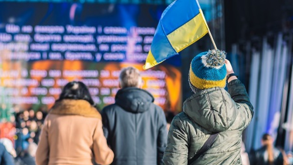 Un enfant avec un drapeau ukrainien regarde la scène