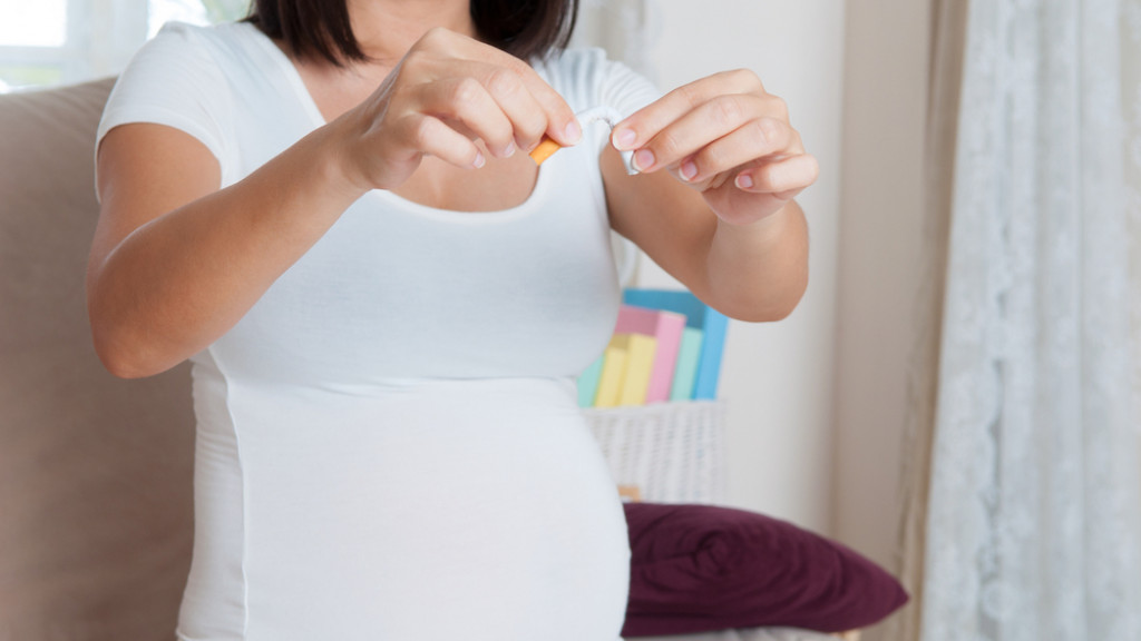 Femme enceinte qui casse une cigarette