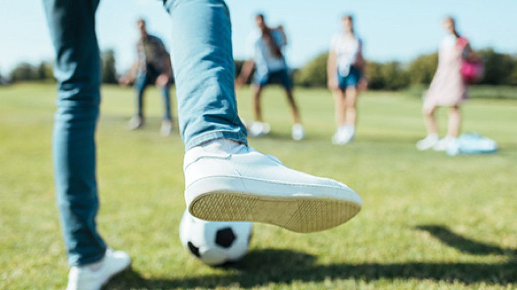 Voet met voetbal gaat trappen naar tieners op een rij
