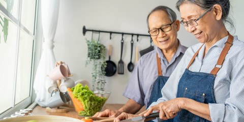 Ouder koppel snijdt samen groenten in de keuken
