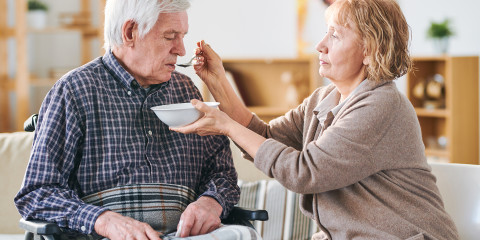 Vrouw helpt oudere man eten