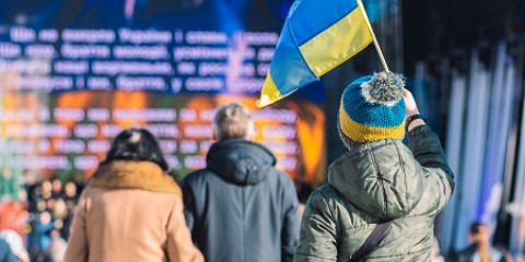 Un enfant avec un drapeau ukrainien regarde la scène