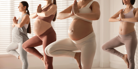 4 zwangere vrouwen staan in yogapose op 1 been