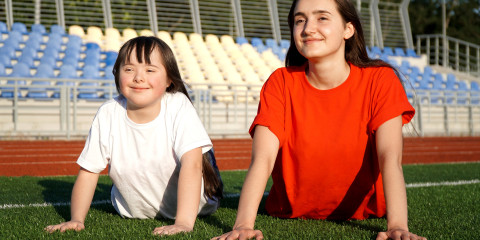 Meisje met beperking en coach sporten op een grasplein