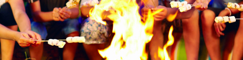 enfants qui réchauffent leurs marshmallows dans un feu de camp