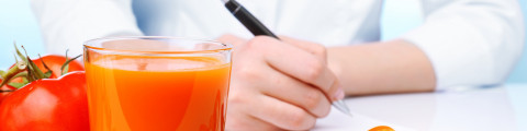 Diététicienne qui élabore un plan diététique avec un jus de tomates et un mètre ruban