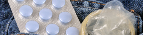 De anticonceptiepil en condoom in achterzak van jeansbroek