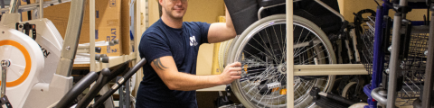 Man van de LM Plus uitleendienst plaatst een rolstoel op het rek in een magazijn.