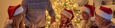 Gezin rond tafel met een kerstboom op de achtergrond