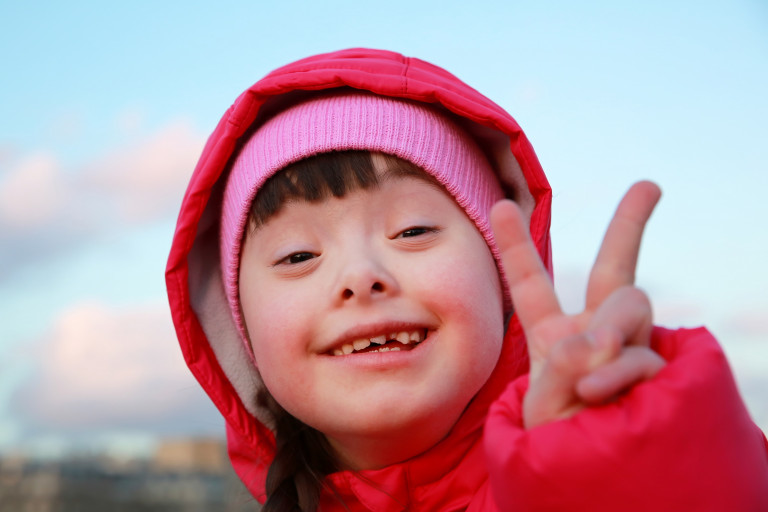 Kind met syndroom van Down maakt V-teken met vingers