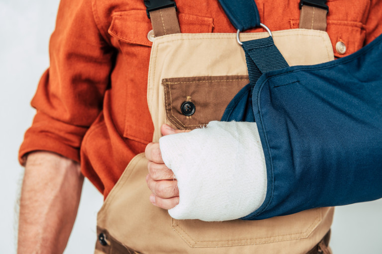 homme en habit de travail avec un bras dans le platre