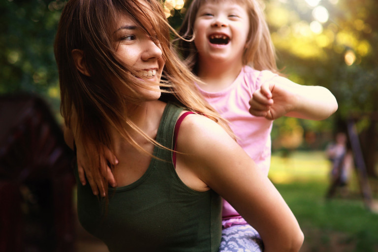 lachend meisje met down met mama in park