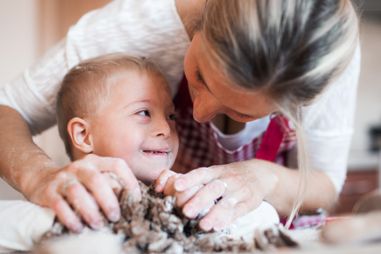 mama helpt kindje met handicap samen koken