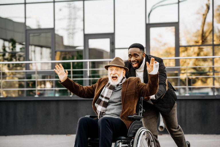 oude man in rolstoel en andere man lachen samen