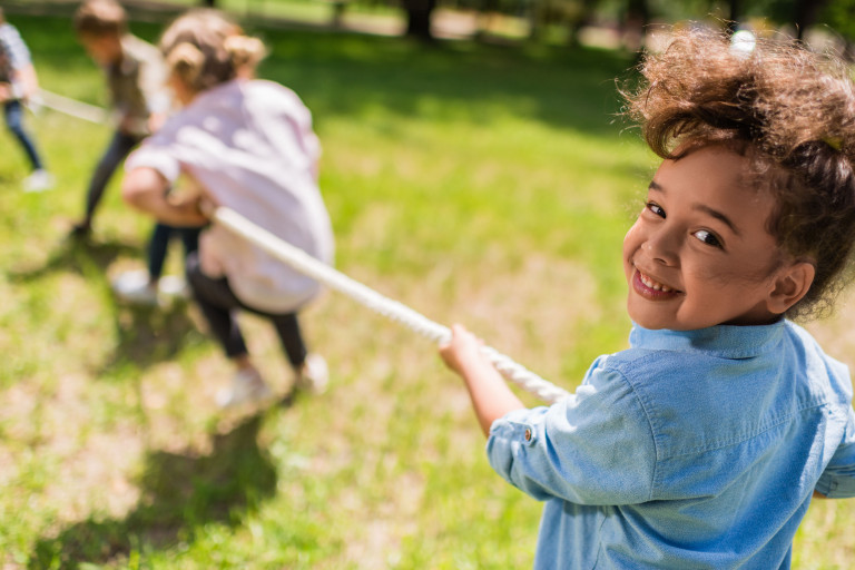 une petite fille joue dehors avec des autres enfants