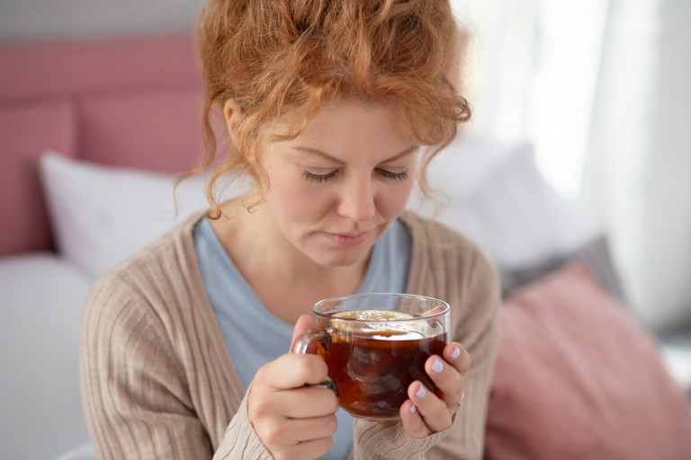 zieke vrouw drinkt thee op bed