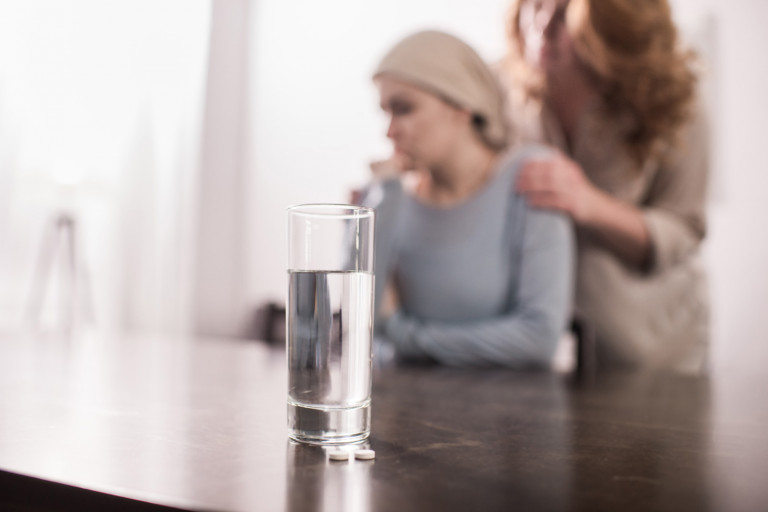 femme atteinte d'un cancer derrière un verre d'eau