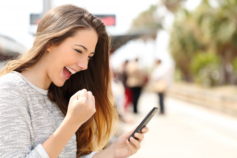 Jonge vrouw happy leest goed nieuws op smartphone