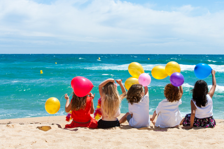 Jeunes enfants assis sur le sable devant la mer